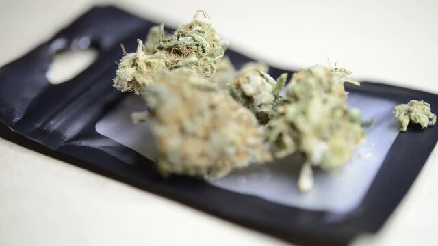 Close up macro rotating shot of ready to smoke marjuana weed buds on a plastic baggie that were grown organically