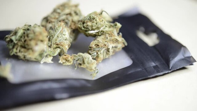 Close up macro rotating shot of ready to smoke marjuana weed buds on top of a small bag that were grown organically