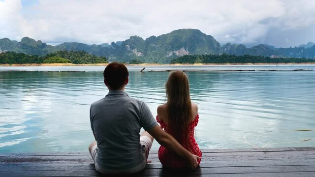 Back View of Couple Sitting Together on River Bridge, Man Flirting, Touching Woman Ass and Getting Slap, Woman Pushing the Man When Friend Trying to Harass She on Date at Nature with Lake and Mountain
