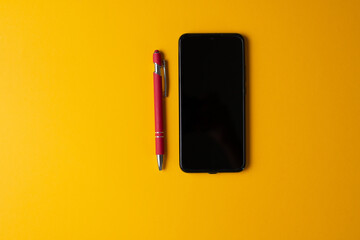 pen and phone on yellow background
