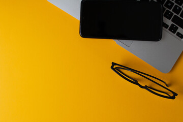 Ordenador portatil y telefono movil en fondo amarillo, concepto trabajar desde casa