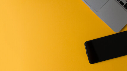 Ordenador portatil y telefono movil en fondo amarillo, concepto trabajar desde casa