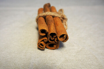 five brown cinnamon sticks are tied with thread on a background of gray linen fabric front view . Christmas symbols