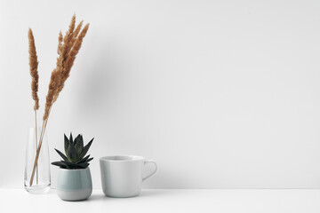A mug, a potted houseplant and a transparent vase. Eco-friendly materials in the decor of the room,...
