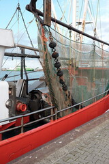 Roter Krabbenkutter mit typischem feinmaschigen Netz im Herbst im Hafen von Neuharlingersiel an der...