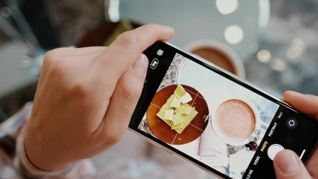 Close-up woman holding modern smartphone and taking pictures of her breakfast to share photos on social networks