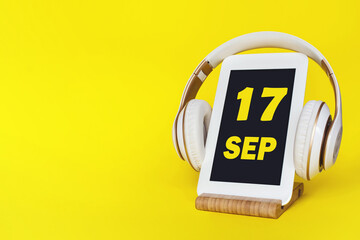 September 17th. Day 17 of month, Calendar date. Stylish headphones and modern tablet on yellow...