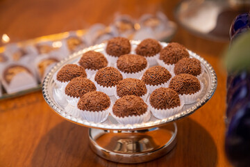Foto feita em um evento social. Vasilha de vidro cheia de brigadeiros para festa.