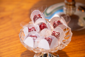 Foto feita em um evento social. Vasilha de vidro cheia de doces para festa.