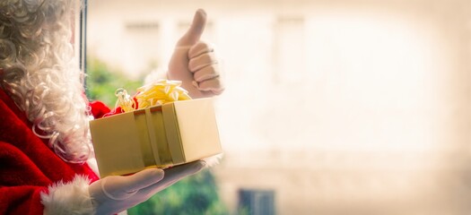 santa claus holding christmas gift box and doing ok sign with fingers