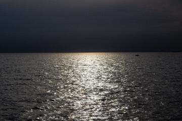 kleines Boot im Sonnenuntergang in der Ferne auf dem Meer