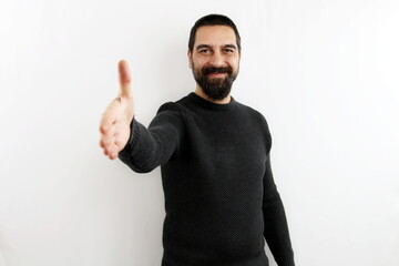 Fototapeta premium Smiling young bearded man on isolated white background smiling stretches out his arm by opening his hand in greeting. Greet, shake hands