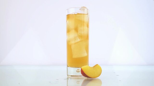 Pouring Peach Ice Tea in a Glass isolated on white Background