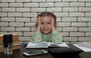 Little girl works in the office. Tired child holds his head and laughs