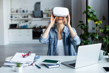 excited blonde woman in vr headset near laptop