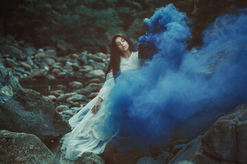Beautiful woman among blue smoke