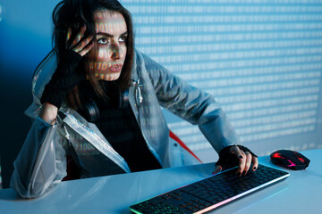 Internet, crime, cyber attack, system breaking concept. Blue neon light background. Woman hacker is working on a code with digital interface all around.