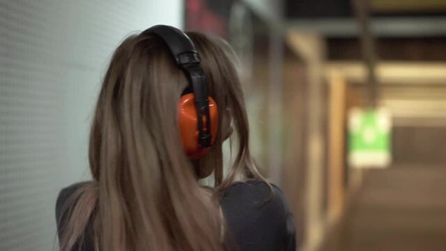 Woman with pistol weapon in hands at shooting range with target, excited and surprised