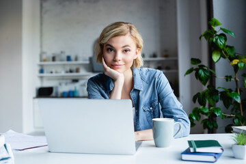 young blonde woman working from home with laptop - obrazy, fototapety, plakaty