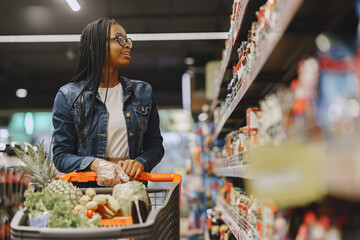 African woman with shopping cart. Girl in a supermarket.