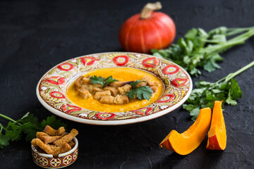 Delicious healthy pumpkin soup, herbs, and ingredients for the dish. Creative atmospheric decoration