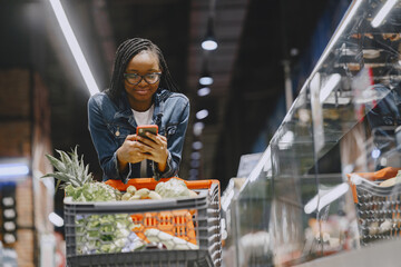 African woman with shopping cart. Girl in a supermarket.