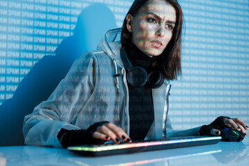 Internet, crime, cyber attack, system breaking concept. Blue neon light background. Woman hacker is working on a code with digital interface all around.