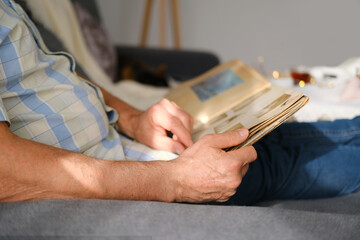 an elderly man looks through an album with old photographs, a concept of memories of youth, childhood, remembering his life, relatives, family connection of generations
