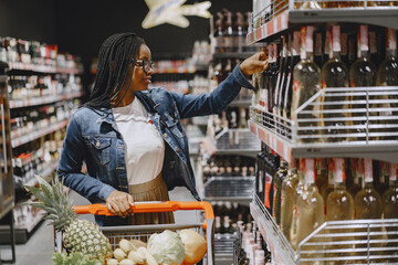 African woman with shopping cart. Girl in a supermarket.