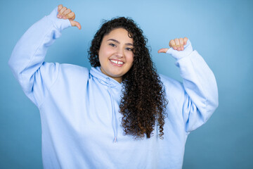 Young beautiful woman wearing casual sweatshirt over isolated blue background looking confident...