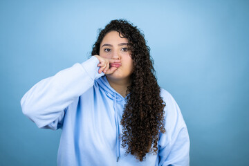 Young beautiful woman wearing casual sweatshirt over isolated blue background mouth and lips shut...