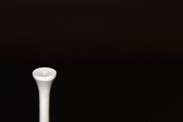 Golf tee against a black background