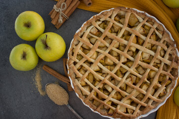 Lattice decorated apple pie on a table. Top view photo of apple tart on yellow fabric background.  Homemade dessert pie close up. 