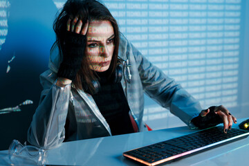 Internet, crime, cyber attack, system breaking concept. Blue neon light background. Woman hacker is working on a code with digital interface all around.