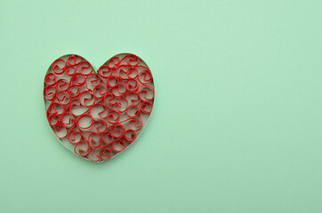 A red origami heart on green background
