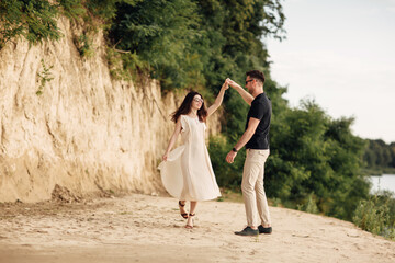 Young couple dancing at beach on sunny day Happy Romantic young Couple Enjoying Beautiful Sunset...