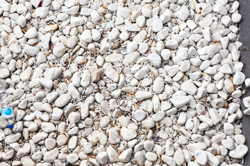 Cigarette butts are in white pebbles, small parts of a cigarette that is left after smoking, background