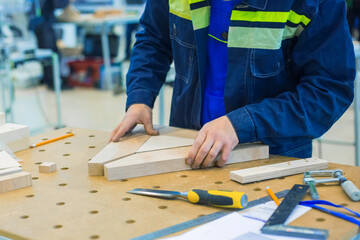 Professional man carpenter working with wooden details on rough workbench at workshop. Design,...