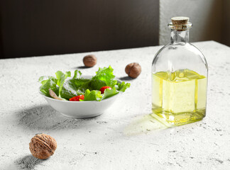 A bottle of walnut oil, walnuts and salad on a gray background, olive oil alternative with unique flavor