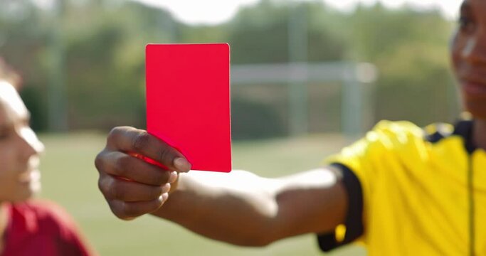 Female referee holding red card to soccer player