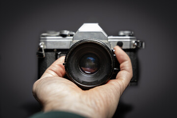 Titel: Old analog camera from the front in the hands of a photographer