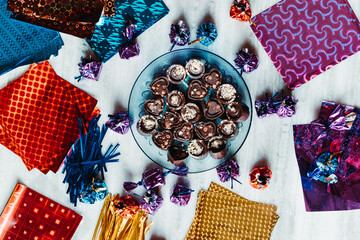 Top view of plate full of chocolates with gift paper and wrapped chocolates in background. Holiday gift concept