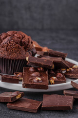 Chocolate cupcake with icing and chocolate bar in Dark lighting,Homemade delicious chocolate muffin on wooden background close-up