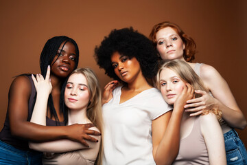 Obraz premium young pretty african and caucasian women posing cheerful together on brown background, lifestyle diverse nationality people concept