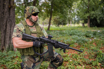 Fototapeta premium Soldier aiming the target. Military action in a forest. Ground gun battle. Fully equipped military forces in operations. Boots on the ground. Airsoft recreation sports. Soldier in tactical equipment.