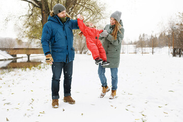 Full height of happy family with one toddler in winter casual outfit walking having fun outdoors