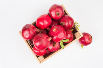 Pomegranate fruits in wooden box on white background