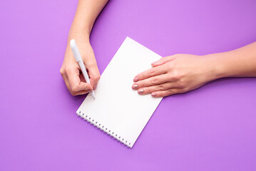 A woman's hand holds a notebook with white sheets on a light background. A place for text, a view from above.