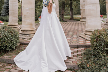 Obraz na płótnie Canvas bride in a wedding dress in columns in the park
