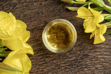 A bowl of evening primrose oil with blooming evening primrose plant